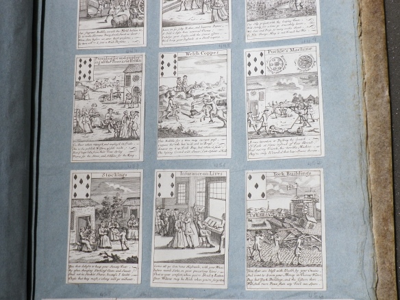 Photograph of engraved playing cards pasted in an album. Each card has a detailed image.